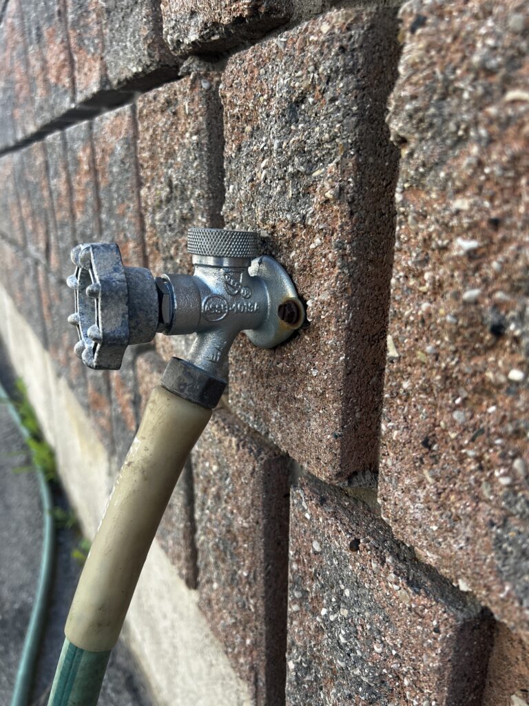 Repaired outdoor frost-free hose bibb spigot mounted on the exterior brick wall of a home in Lambeth, Ontario.