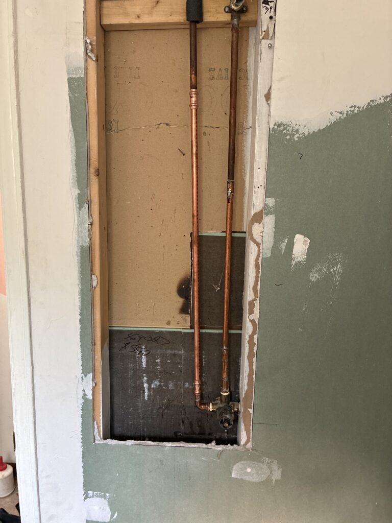 Newly installed brass shower valve connected with durable copper piping inside open wall framing in St. Thomas, Ontario.