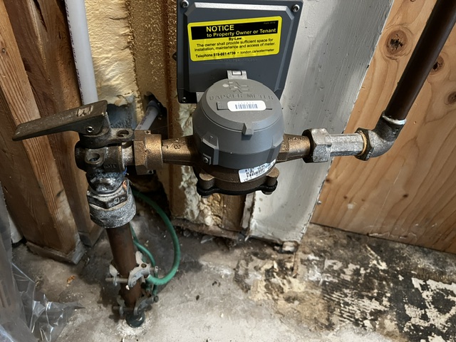 Indoor brass Badger water meter connected to a copper main supply line with a city shut-off valve in a London, Ontario home.